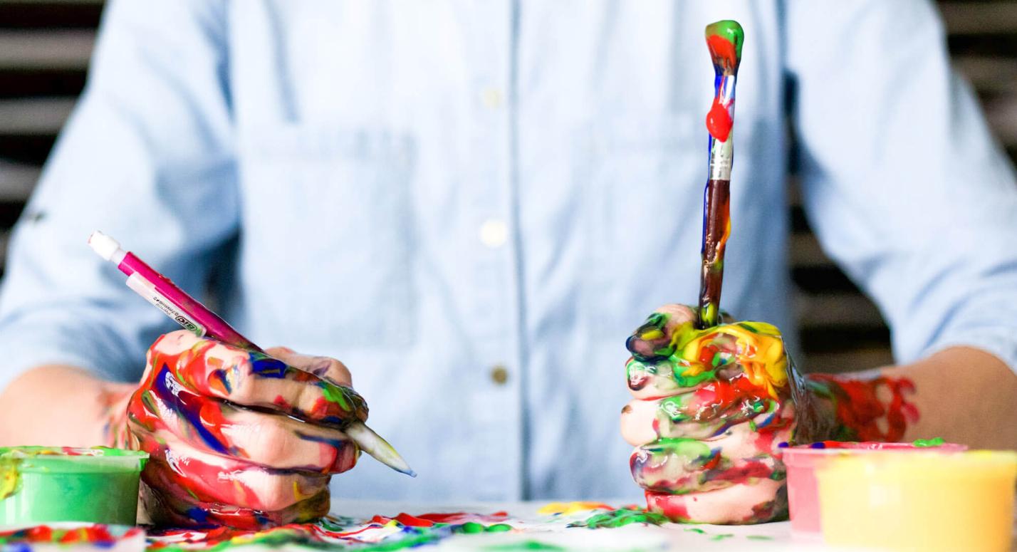 Kreative Person mit Händen voller Farbe