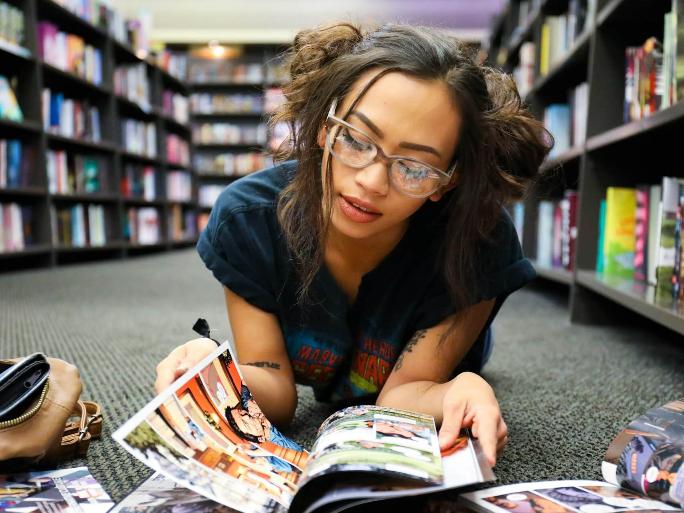 Eine junge Frau liegt auf dem Boden und liest Bücher